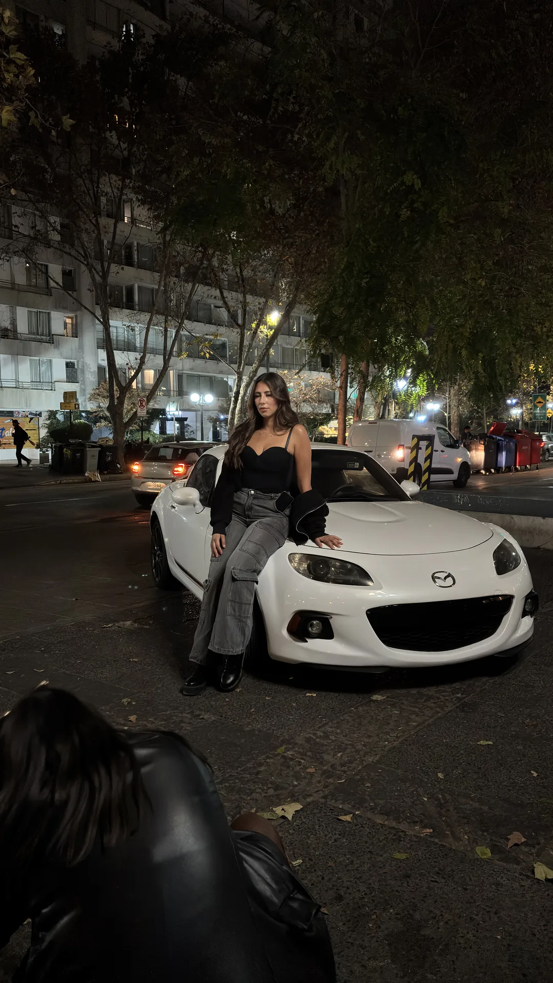 Modelo sobre el MX-5 blanco en una calle de la ciudad de noche